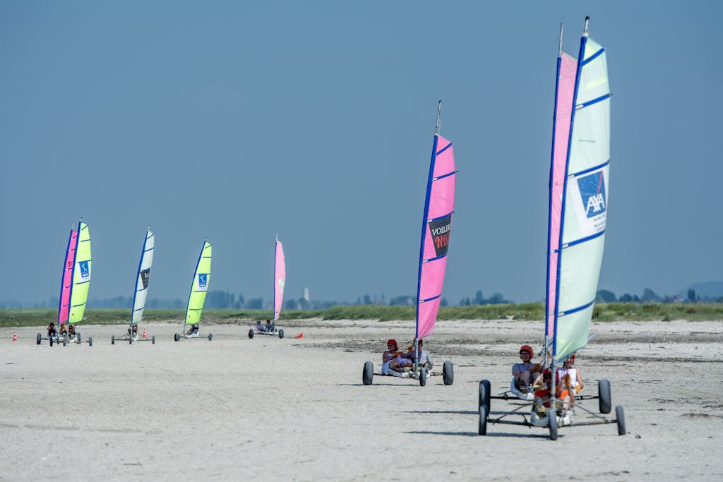 Colorful land yachting event on a sandy beach, showcasing vibrant sails and excitement of motorsport racing.